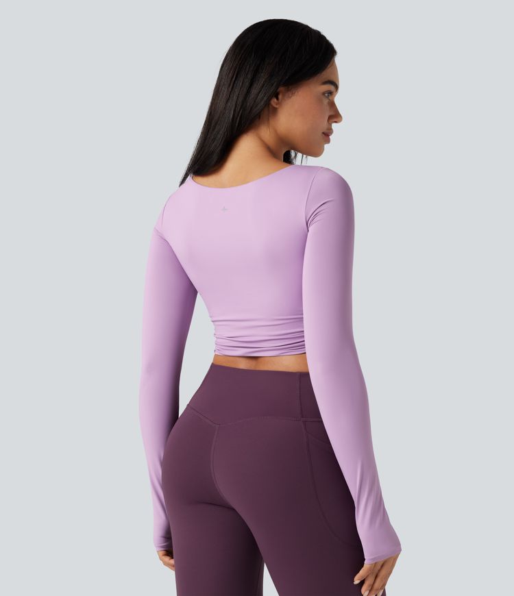 push-up-top mit vorgeformtem spacer rundhalsausschnitt langen Ärmeln und daumenlöchern kurzem schnitt und überkreuztem bein – ideal für yoga und sport.